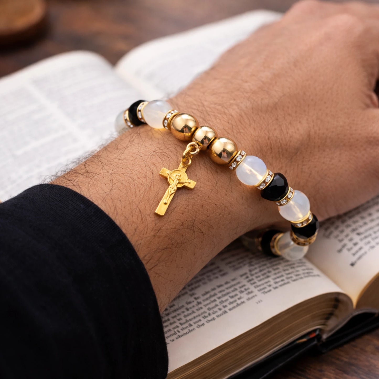 Bracelet with gold cross charm on wrist over an open book