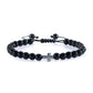 Black beaded bracelet with a silver cross charm on a white background