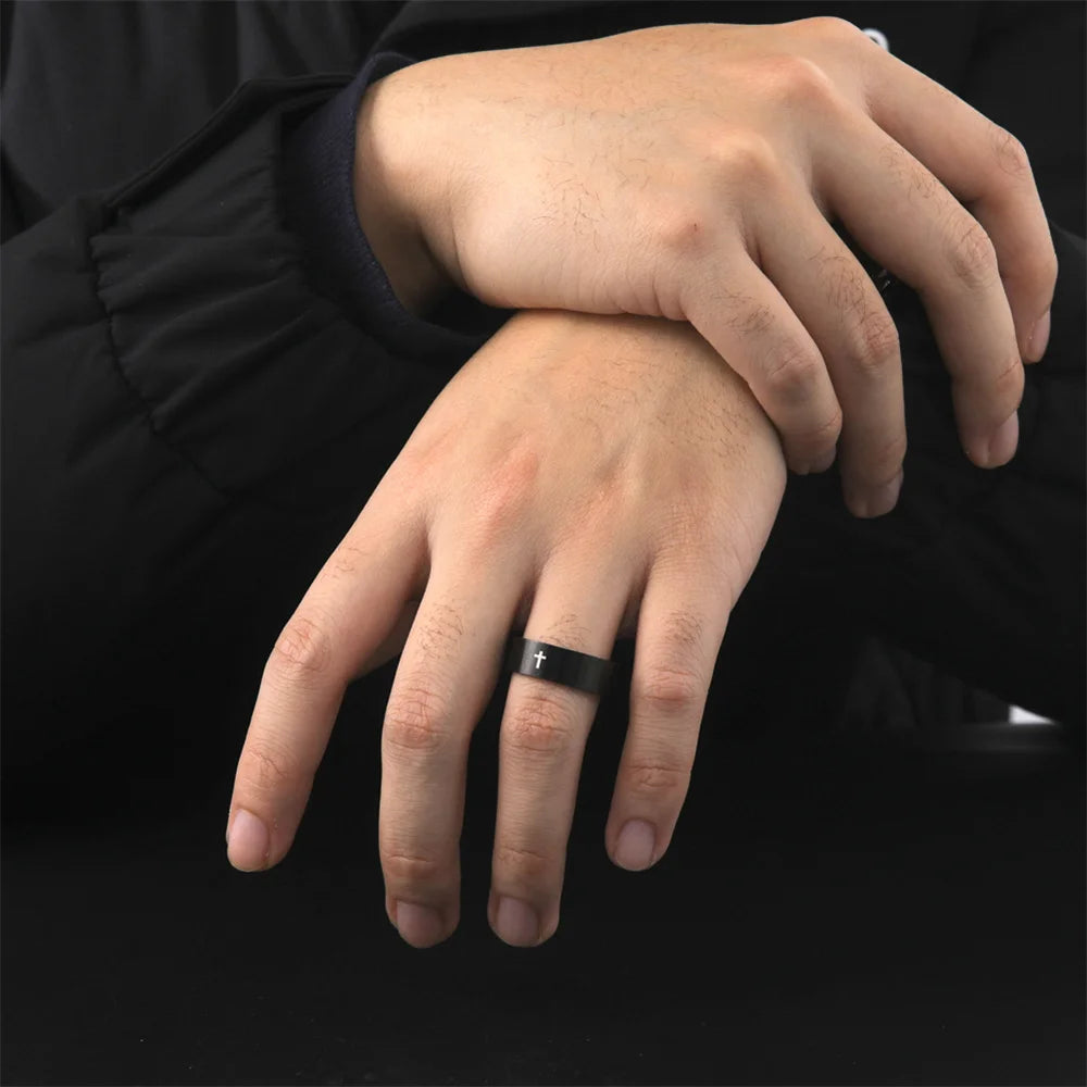 Close-up of a hand wearing a black ring on a black background