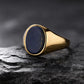Gold ring with a dark blue stone on a black stone surface