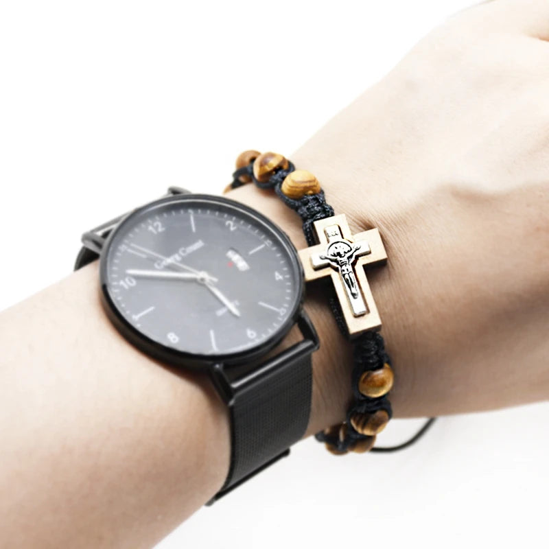 Wrist with black watch and wooden bracelet featuring a cross on a white background