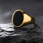 Gold ring with a black stone on a dark textured surface