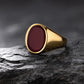 Gold ring with a red stone on a dark stone surface