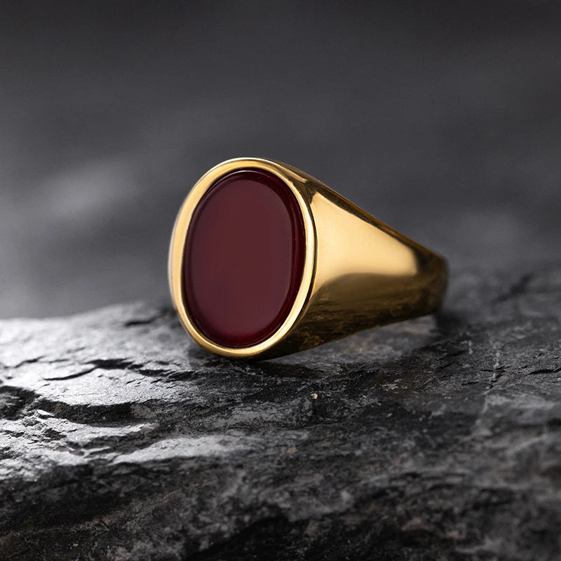 Gold ring with a red stone on a dark stone surface