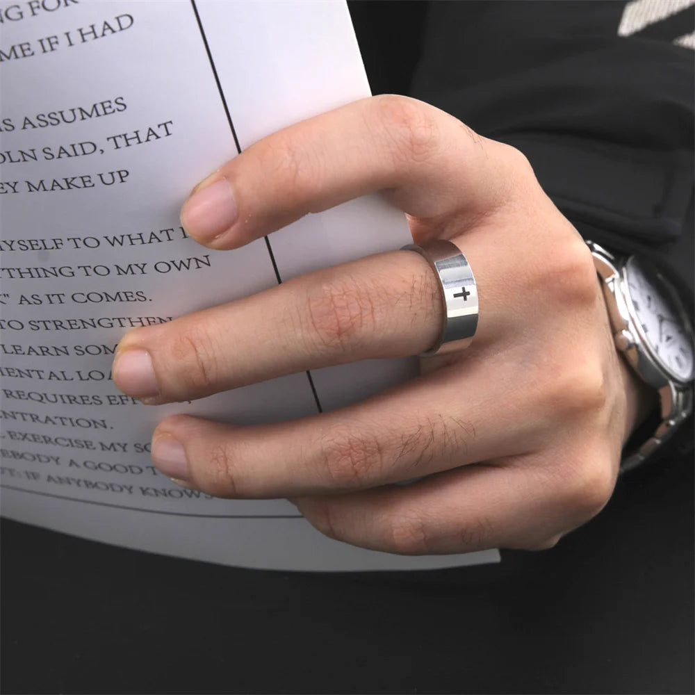 Hand wearing a silver ring with a cross design, holding a book.