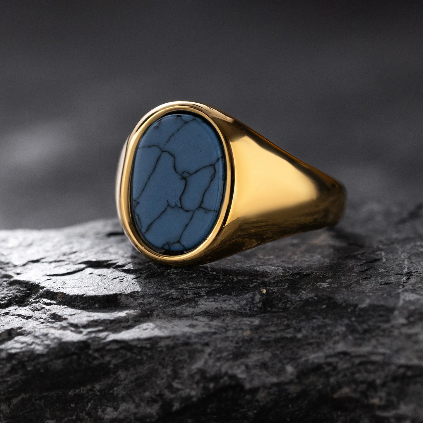 Gold ring with a blue stone on a dark textured surface